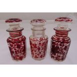 Three hand decorated faceted glass jars with drop stoppers, 17cm (h)