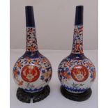 A pair of oriental vases with elongated necks, the sides decorated with flowers and leaves on carved