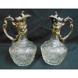 A pair of continental cut glass claret jugs with silver plated scroll handles and hinged covers 27cm