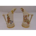A pair of Royal Worcester blush ivory jugs decorated with flowers, leaves and gilded bases, marks to