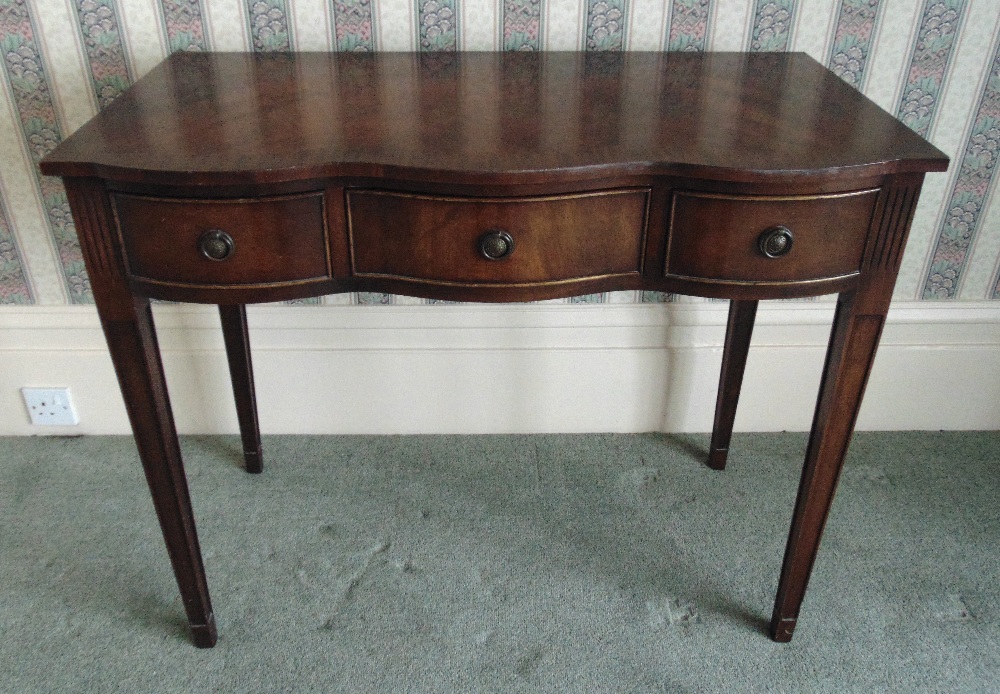 A mahogany serpentine fronted hall table the three drawers with brass swing handles on four tapering