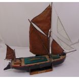 A wooden model of a sailing boat with electric motor and linen sails on rectangular wood stand, 72 x