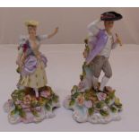 A pair of Sitzendorf candlesticks with applied figures of a man and lady on floral bases, marks to