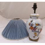 A porcelain baluster table lamp decorated with flowers and leaves mounted on a gilded metal base