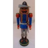A carved painted wooden German nutcracker in the form of a soldier on raised circular base, 53cm (
