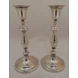A pair of hallmarked silver table candlesticks of baluster form on raised circular weighted bases,