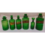 Six Victorian green ribbed glass apothecary bottles with drop stoppers, one stopper with an eye bath