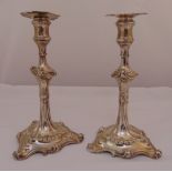 A pair of George III hallmarked silver table candlesticks in Rococo style with beaded and scroll