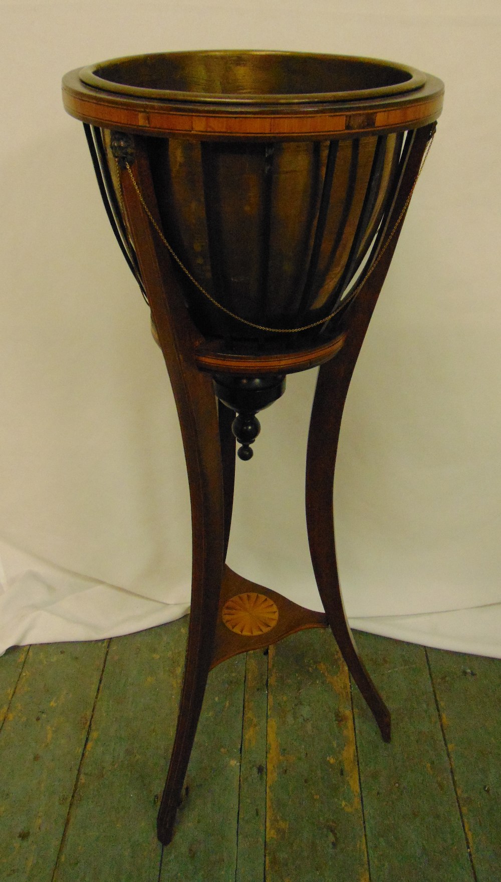 An Edwardian circular mahogany and satinwood inlaid jardiniŠre on three outswept legs to include