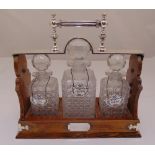 A three bottle Tantalus mahogany case with silver plated top and handle and three enamel wine