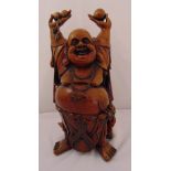 A carved wooden laughing Buddha, the raised arms supporting fruits, 59cm (h)