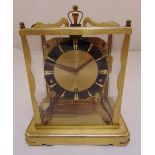 A gilded metal rectangular four glass chiming mantle clock with black chapter ring on raised