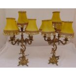 A pair of gilt metal table lamps, the scrolling arms supported by putti on raised bases with four