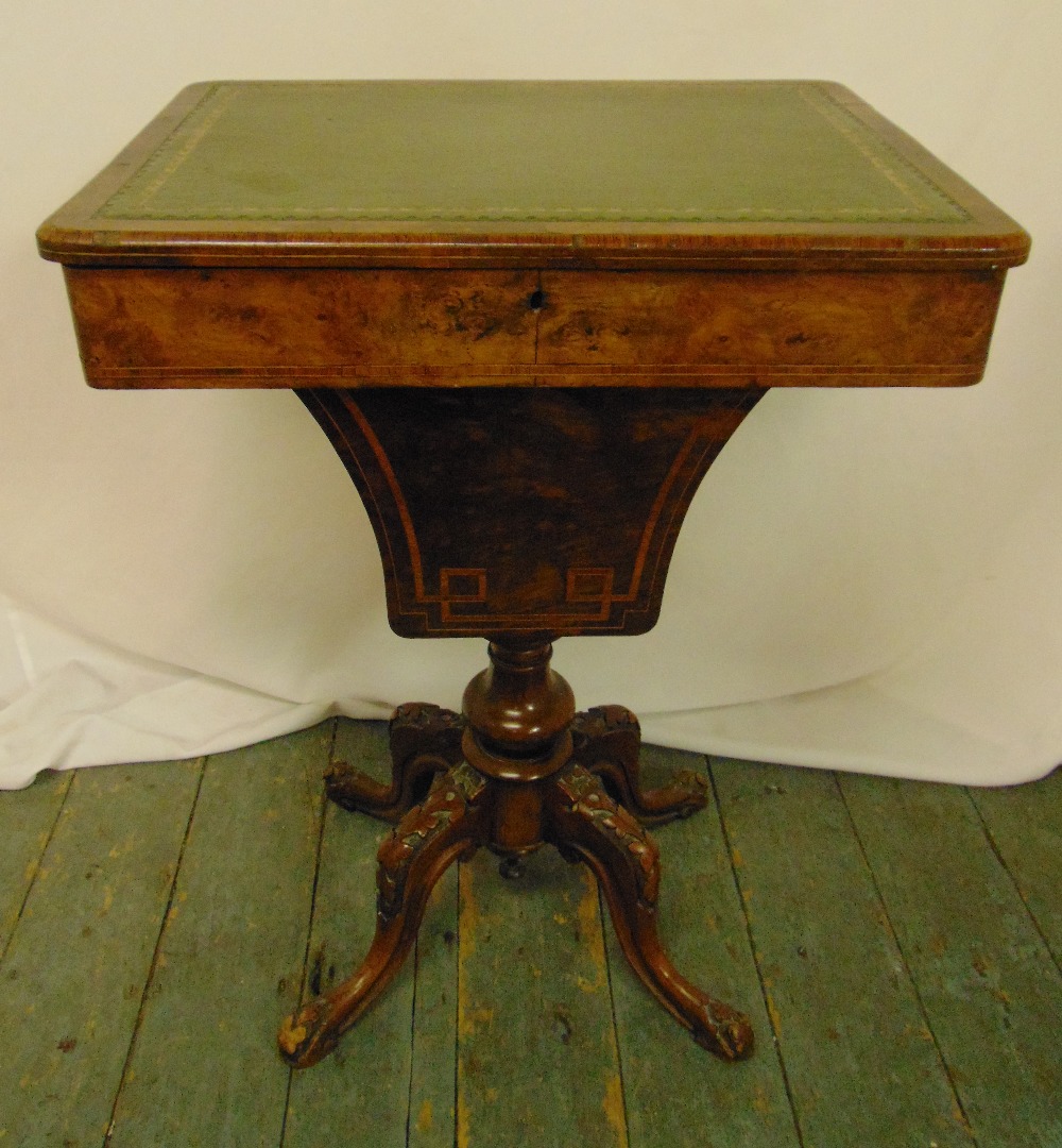 A Victorian rectangular walnut work table with hinged inset leather top on four carved scrolling