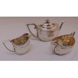 A hallmarked silver three piece teaset, oval panelled form with angled handles to include a