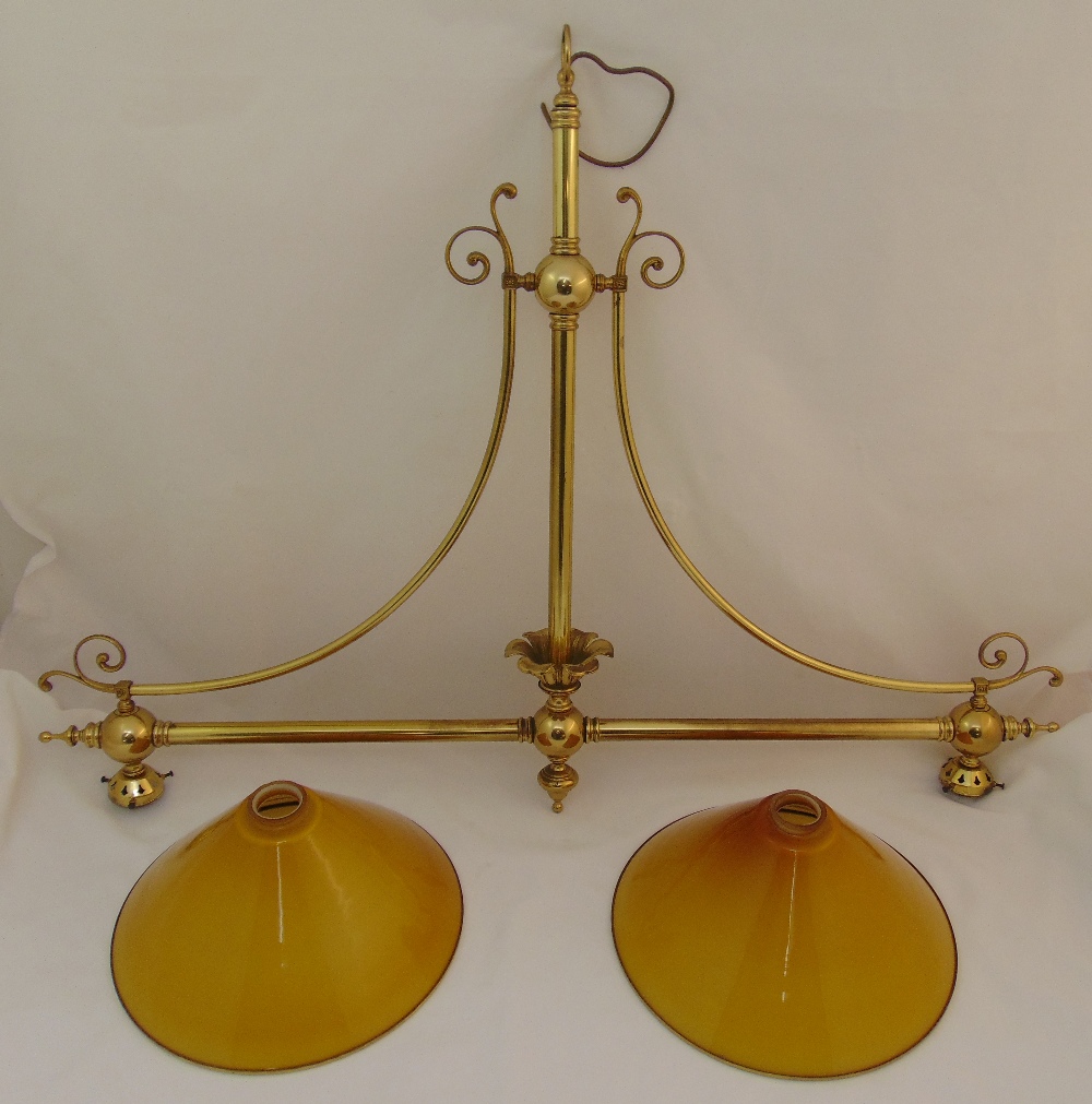 A brass snooker table light, the scrolling arms supporting two glass shades, 92 x 117cm