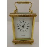 A brass carriage clock of customary form, white enamel dial with Roman numerals on four bun feet, to