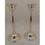 A pair of hallmarked silver table candlesticks of panelled baluster form on raised circular bases,