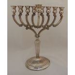 A white metal Menorah, the scrolling arms on tapering fluted stem and raised circular base with