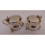 A pair of hallmarked silver mustard pots, baluster form with gadrooned borders, hinged covers on