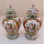 A pair of porcelain oriental style baluster vases with pull off covers decorated with birds, flowers