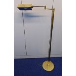 A brass free standing reading light of tubular form, rectangular shade with hinged arm all on