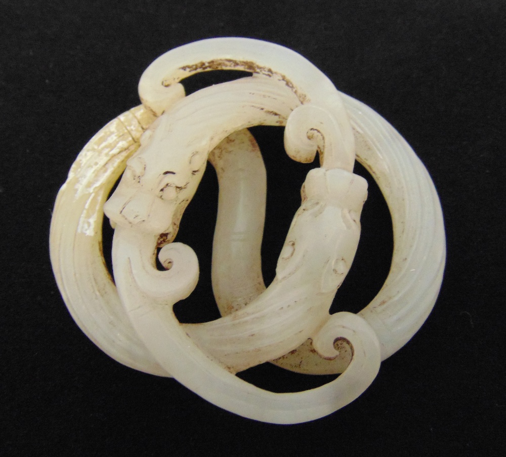 A Chinese Qing Dynasty white jade pendant in the form of interlocking serpents, 6cm (dia)