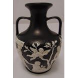 An early 19th century Wedgwood Portland black basalt vase, with raised white putti and classical