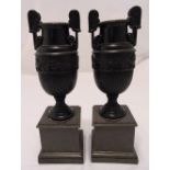 A pair of composite classical urns on raised moulded square plinths, 38cm (h)