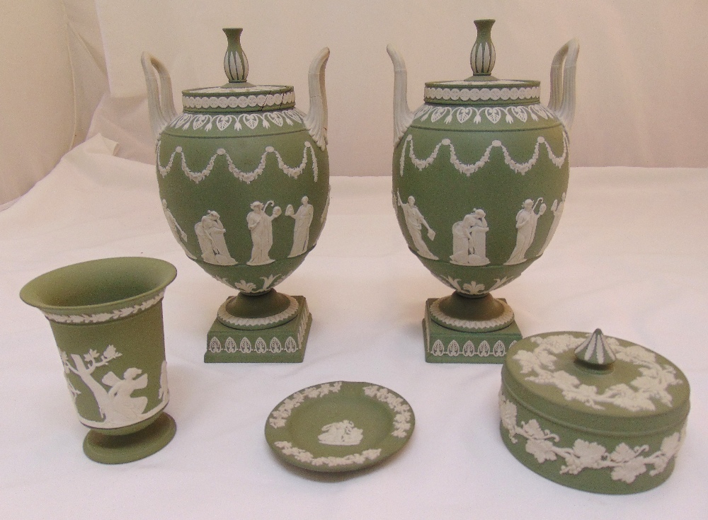 A pair of Wedgwood green Jasperware two handled urns and covers, one cover crack to rim, 32cm (h), a