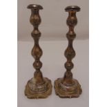 A pair of hallmarked silver table candlesticks baluster stems on shaped square bases, London 1922,