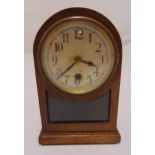 An oak cased mantle clock of arched rectangular form, the circular dial with Arabic numerals on