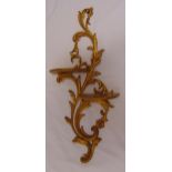 A gilt metal double wall bracket of scrolling leaf design supporting two wooden demi-lune shelves,