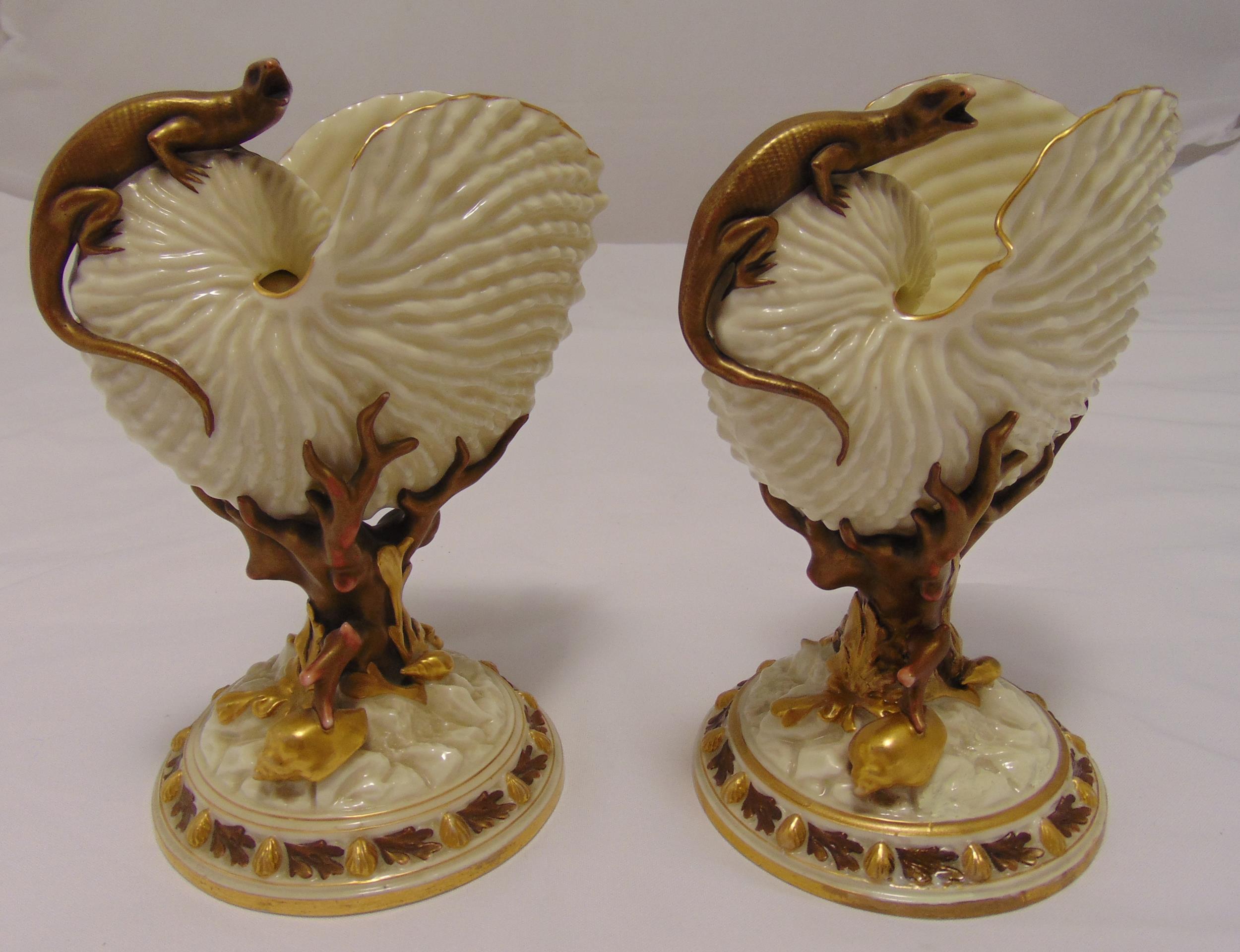 A pair of Royal Worcester Nautilus shell vases with applied lizards and coral supports on raised