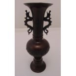 An oriental bronze vase of trumpet form with scroll pierced side handles on raised circular base,