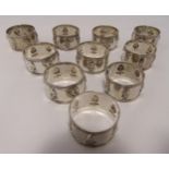 A set of ten white metal napkin rings, decorated with stylised fruit within milled borders