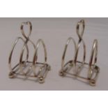 A pair of hallmarked silver heart shaped toast racks with central handle on four ball feet,