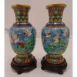 A pair of oriental cloisonné vases of baluster form, the sides decorated with birds in flight on