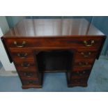 A rectangular mahogany kneehole desk with drop flap to the sides, nine drawers with brass swing