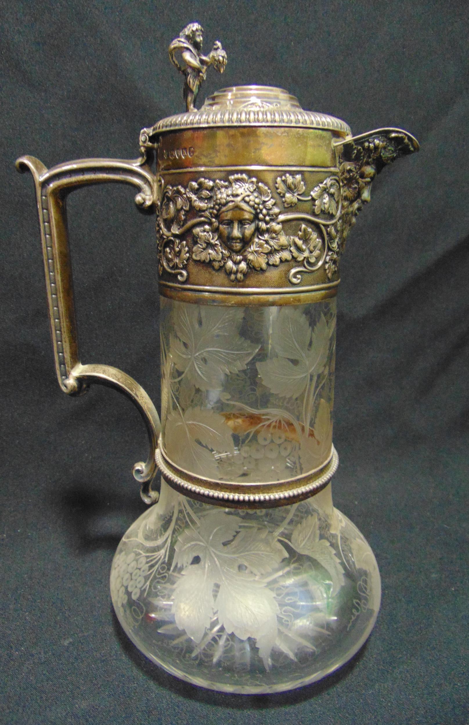 A Victorian hallmarked silver and glass claret jug, the body etched with grapes and vine leaves, the
