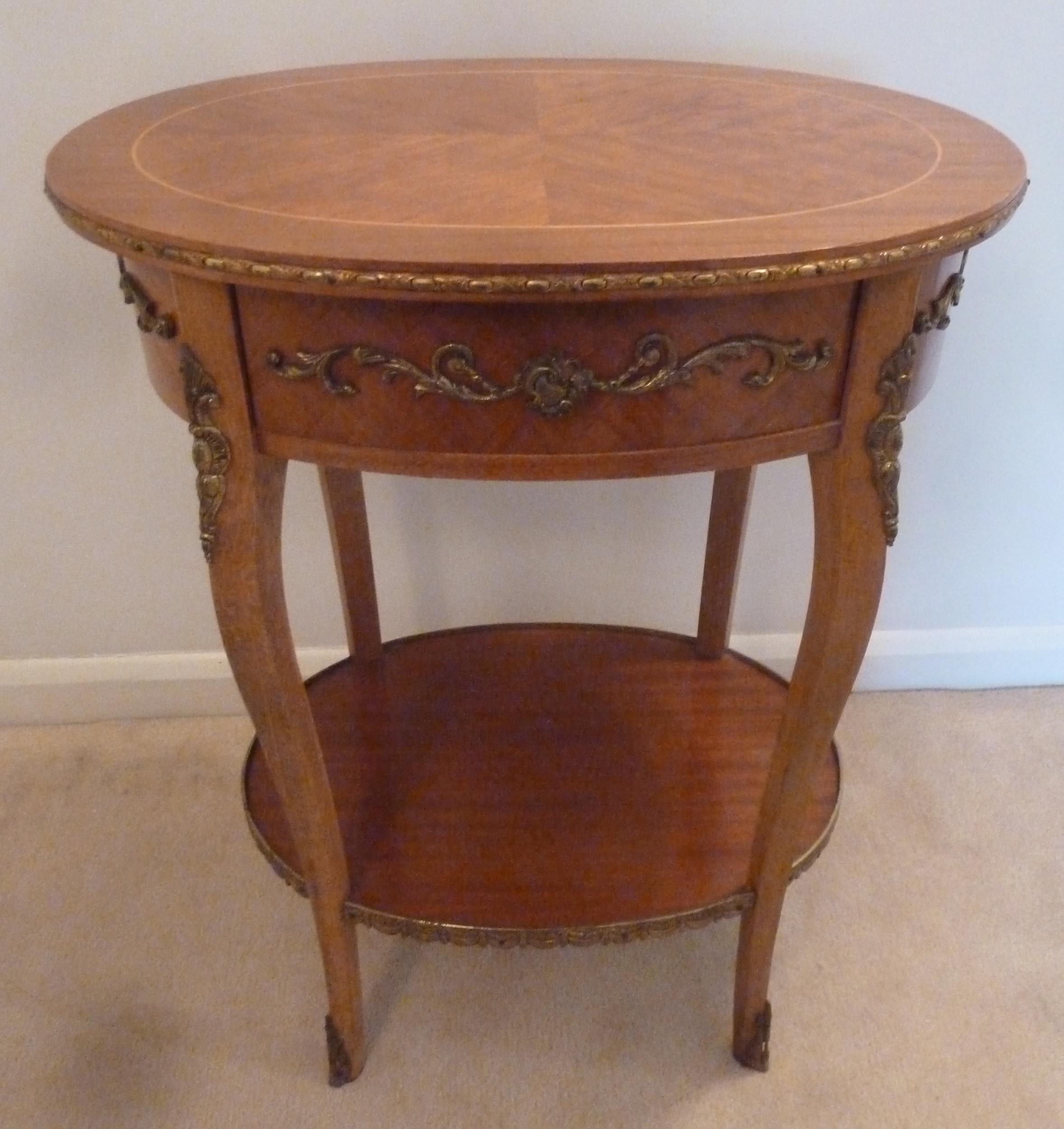 An oval mahogany and Kingswood side table with applied gilded mounts and a single drawer on four