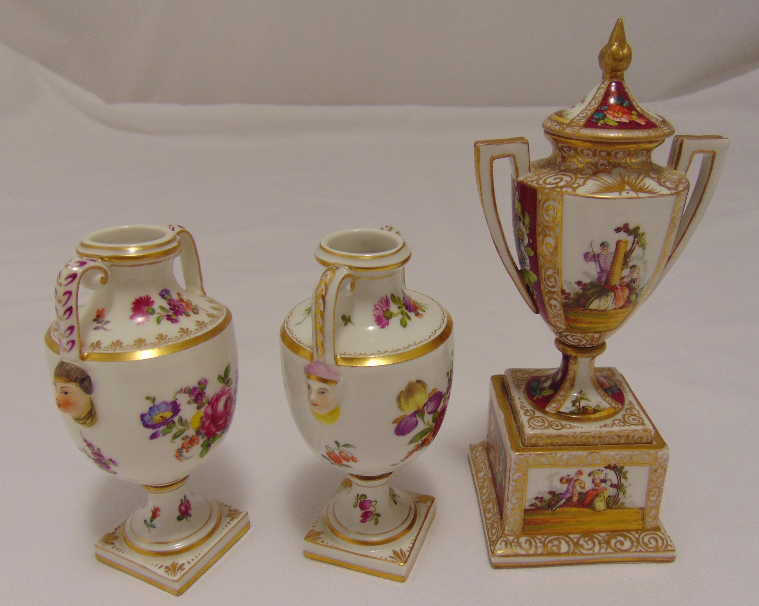 A pair of Dresden two handled vases decorated with flowers, leaves and masks below side handles