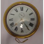 A brass circular ships clock mounted on a wooden plinth, white enamel dial with Roman numerals, 23cm