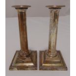 A pair of Victorian hallmarked silver table candlesticks of faceted columnar form on raised square