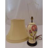 A Moorcroft baluster form table lamp decorated with flowers and leaves mounted on circular wooden