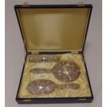 A cased hallmarked silver dressing table set comprising a hand mirror, a hair brush and a clothes