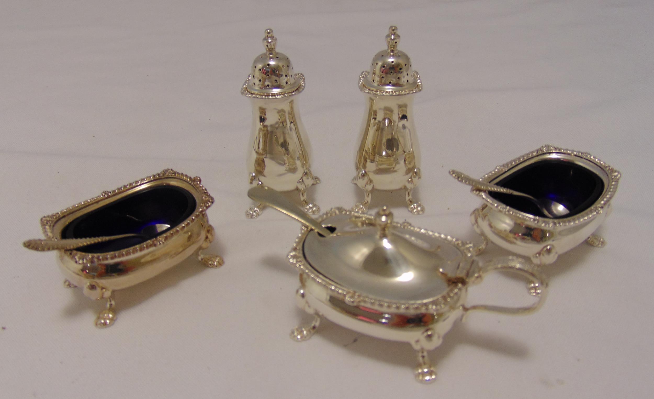 A hallmarked silver five piece condiment set to include blue glass liners and three condiment
