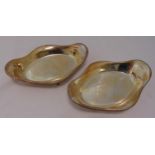A pair of hallmarked silver roll baskets, oval with gadrooned borders on four stepped hoof feet,