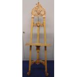 An Art Nouveau style blonde wood picture easel, carved with scrolls and leaves, 190 x 59.5cm