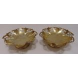 A pair of hallmarked silver circular bonbon dishes, the scroll pierced lobed sides on raised